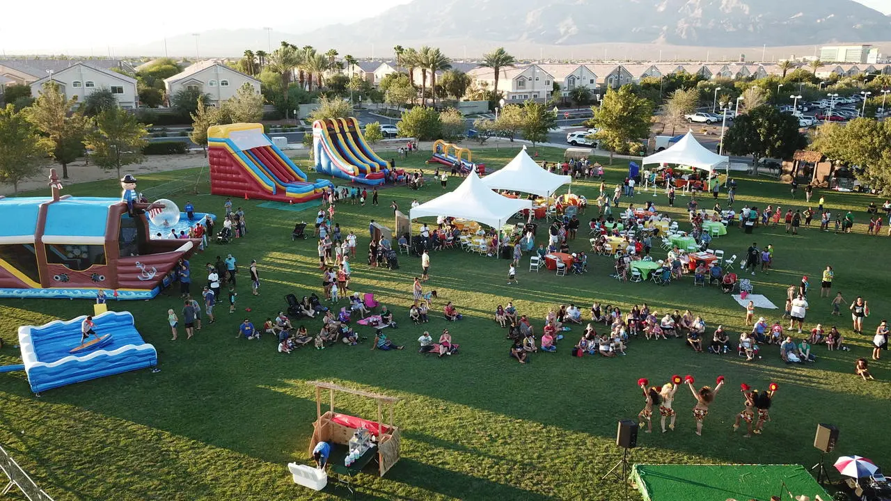 HOA community picnic outdoor fair with inflatable attractions, tents, and stage entertainment